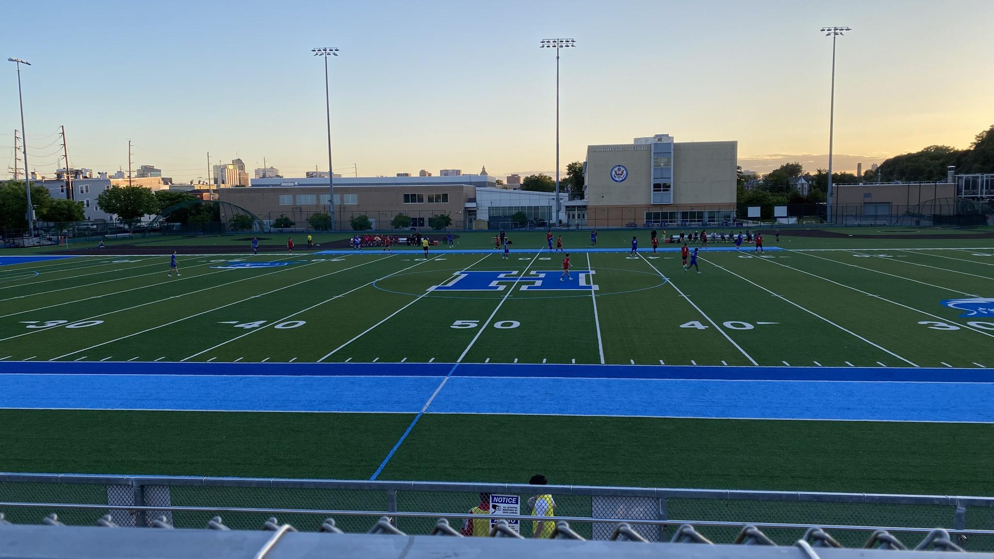 An image of Harrison High School and its athletic field with the Newark skyline visible on the left side of the image