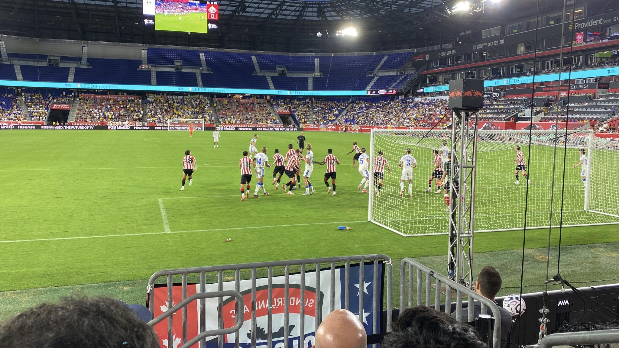An image of players jockeying for position as a corner kick falls into the box