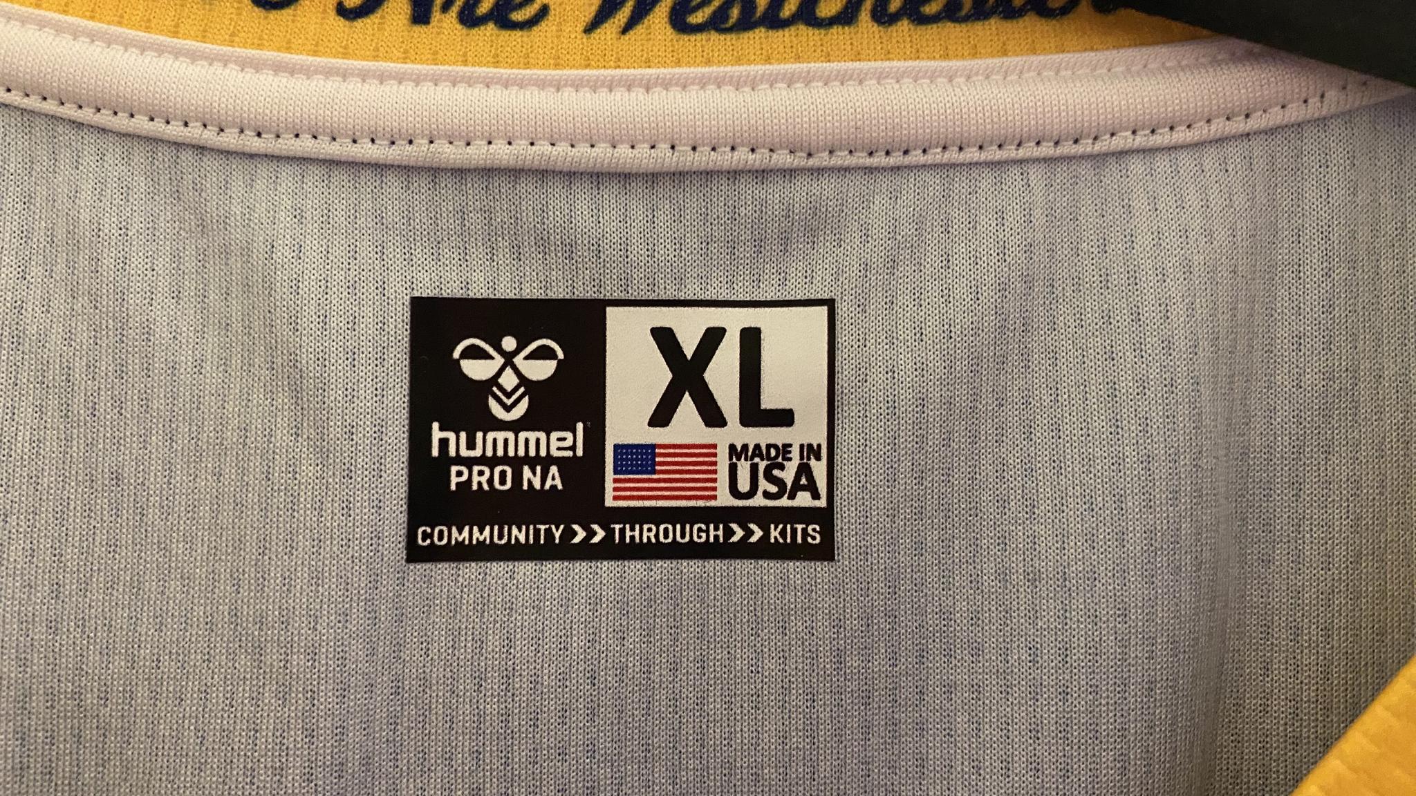 An image of the inside of a Hummel shirt made in the US. It has an American Flag and a prominent "XL" along with "MADE IN USA"