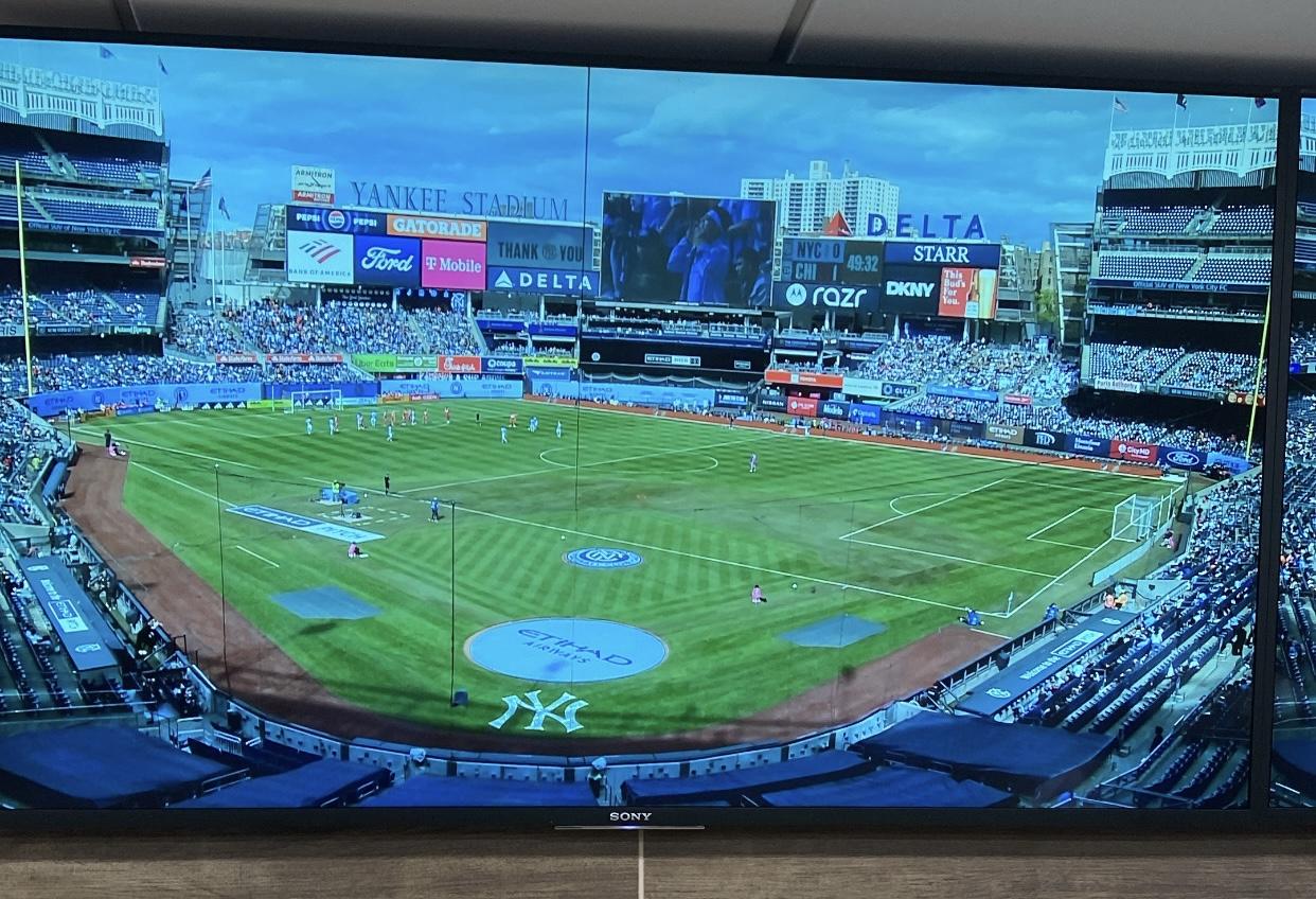 A photo of a camera feed from behind home plate at Yankee Stadium. The purpose of this photo is to illustrate how unusual the soccer layout is.
