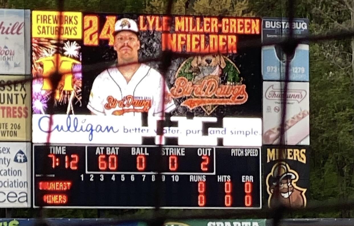 An image of the electronic scoreboard and video board at Skylands Stadium. The video board is displaying a player named Lyle Miller-Green, but several panels of the video board are not working properly.